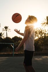 Boy playing with ball on basketball court