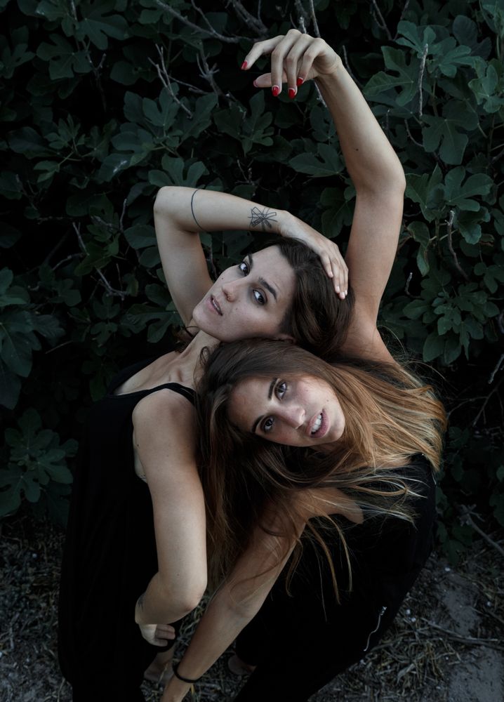 Young women posing near green bush