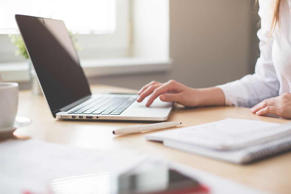 Cropped image of woman in light top working on computer in an office