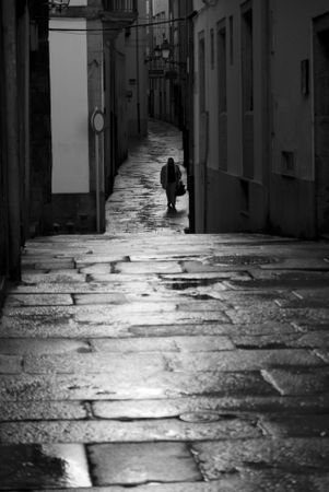 Grayscale photo of a person walking in an alley