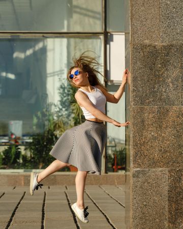 Female in dancing leap near marble column