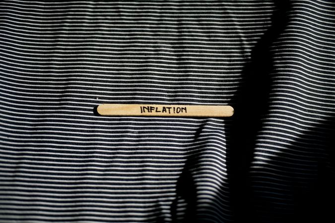 The word “inflation” written on wooden stick laying on striped fabric