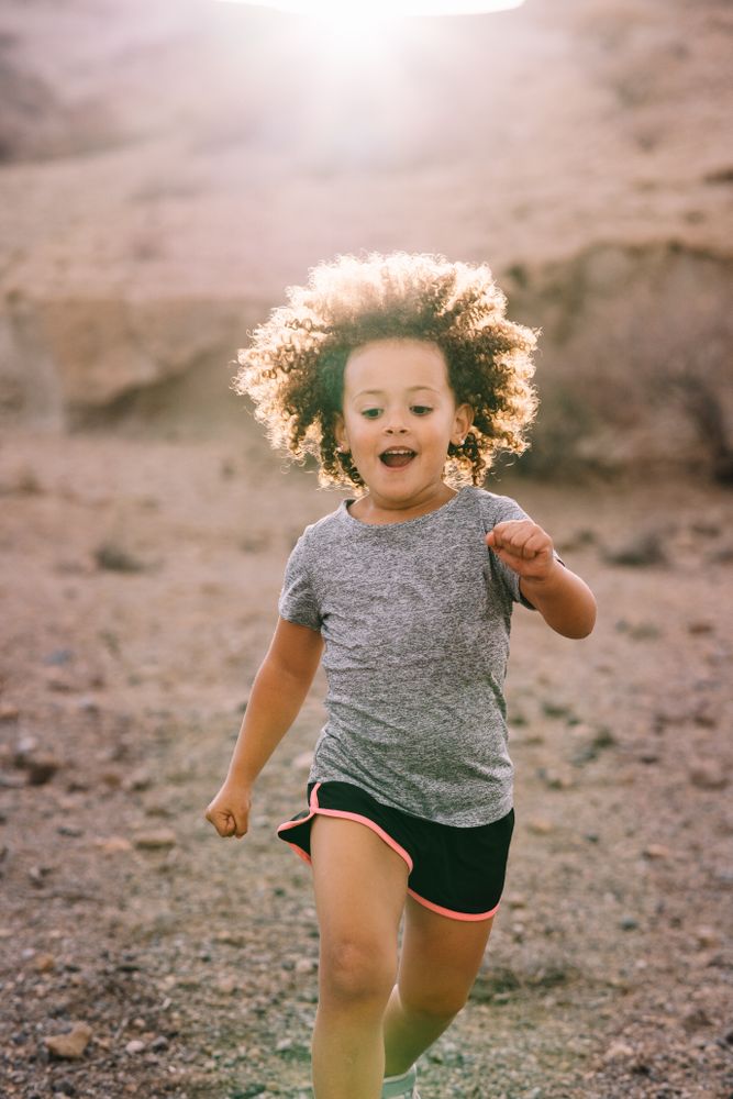 Happy curly toddler running on nature