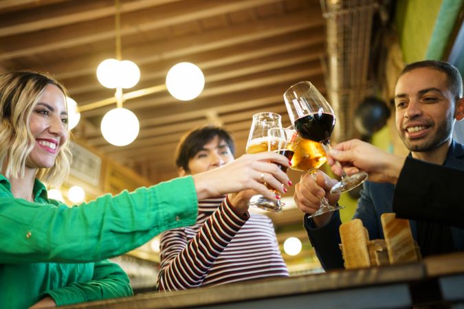 Group of friends toasting beer and wine in bar