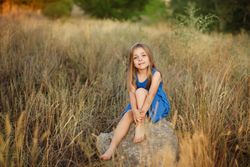 Female child sitting on bolder in field