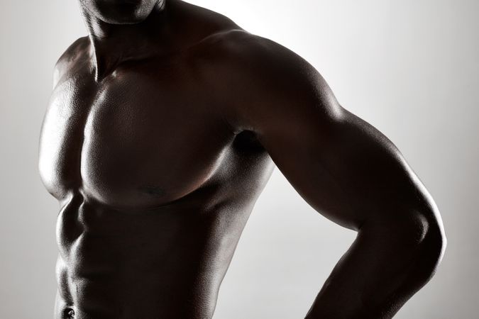 Close up shot of athletic man with muscular body against grey background