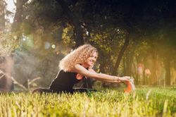Happy woman stretching on sunny meadow