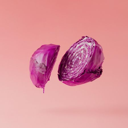 Red cabbage halved on pastel pink background