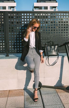 Businesswoman with mobile and her scooter next