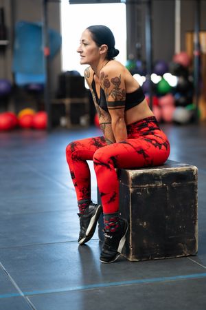 Relaxed sportswoman sitting on a box in the gym