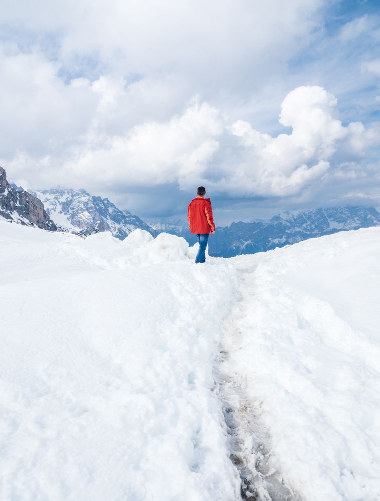 Unrecognizable lonely traveler walking on snowy hill