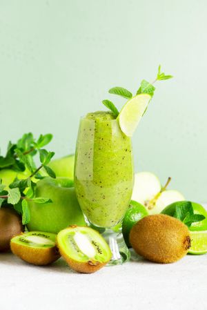 Blended kiwi and apple juice in tall glass, vertical