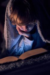 Boy reading book in darkness