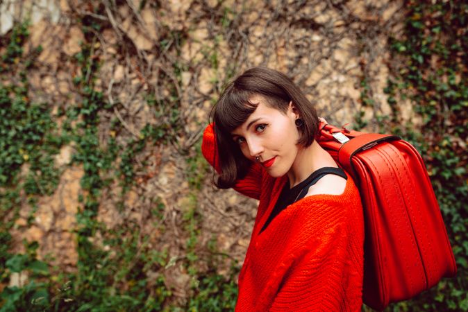Woman in red with big red suitcase in forest