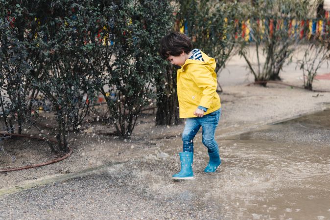 Happy kid jumping on puddle