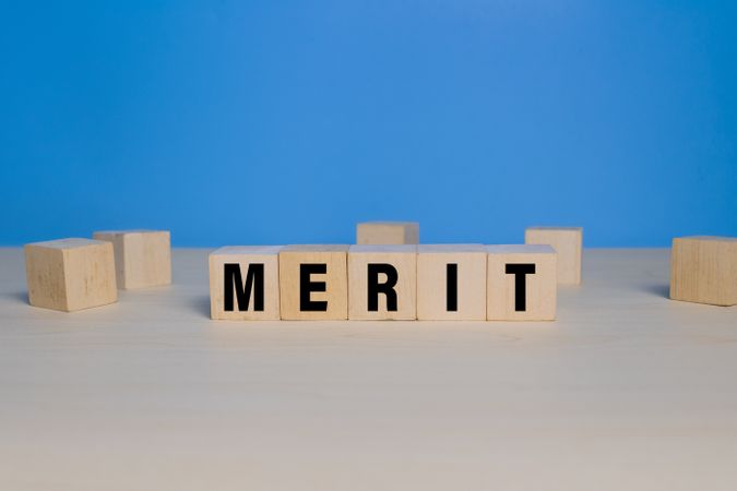 merit word text on wooden blocks isolated on blue background
