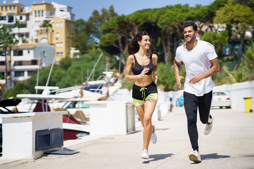 Happy man and woman jogging on pier