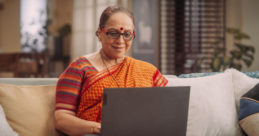 Portrait of Older Indian Woman Using Laptop Searching and Sharing Traditional Recepe