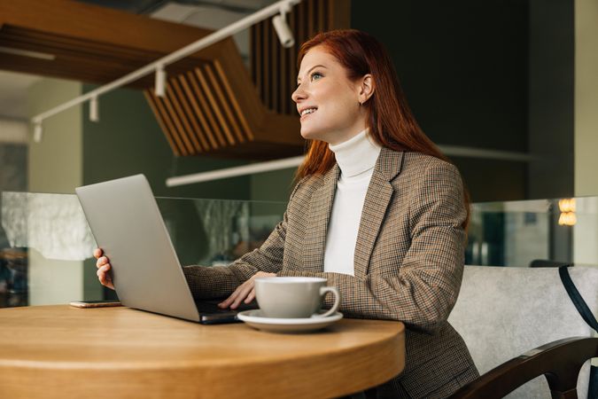 Woman entrepreneur sitting at a table with a laptop and mug of coffee