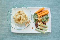 Hummus and sliced vegetables on plate