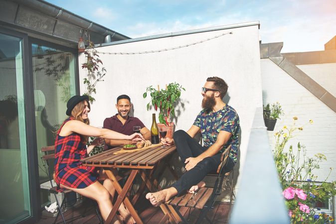 Three friends on rooftop on sunny day with red wine