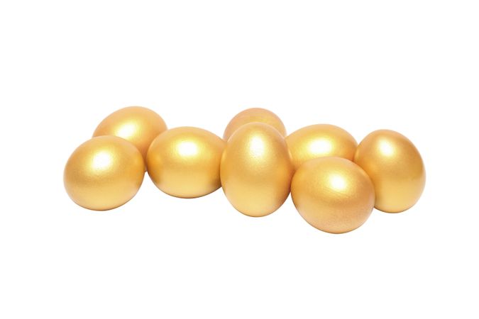 Concept of wealth and retirement - golden eggs, isolated on light background
