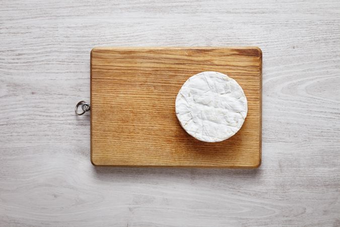 Whole wheel of brie cheese on wooden board