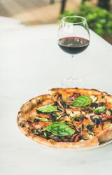 Wood fire oven cooked pizza with glass of red wine