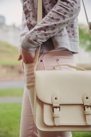 Woman wearing cardigan, pink jeans and satchel bag standing outside