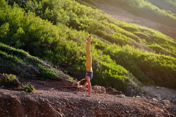 Young woman taking Handstand pose in nature