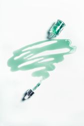 Blue cosmetic liquid leaking from glass pipette bottle. Moisturizing beauty product for facial treatment. Top view.
