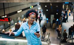 Woman looking at cellphone on escalator exiting the subway