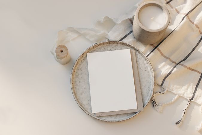 Blank greeting card with craft paper envelope on ceramic plate