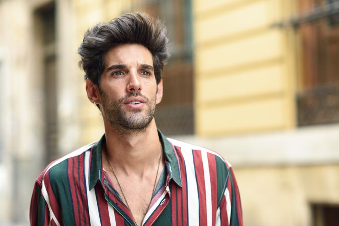 Portrait of curious dark haired man standing outside looking in the distance