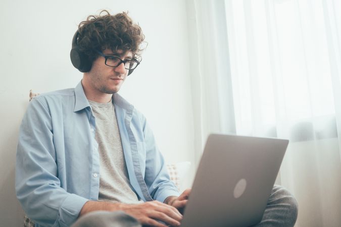Freelancer worker listening to music working on laptop at home