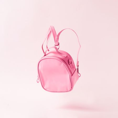 Pastel pink backpack floating on pink background