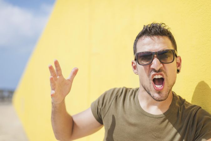 Male yelling in front of yellow wall outside