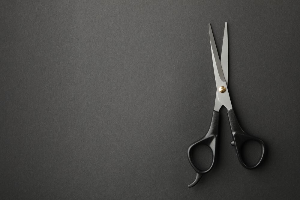 hairdresser scissors on dark background, space for text