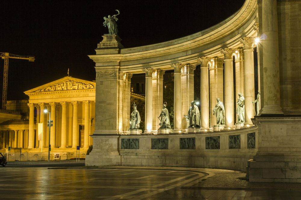 Columns from Heroes Square lit up at night