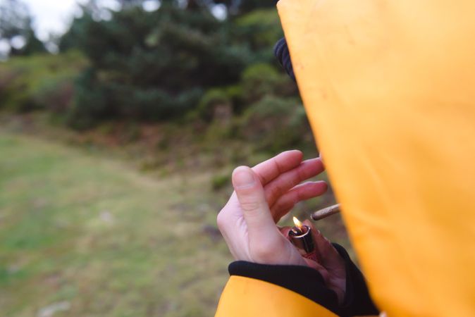 Person in yellow raincoat lightening cigarette
