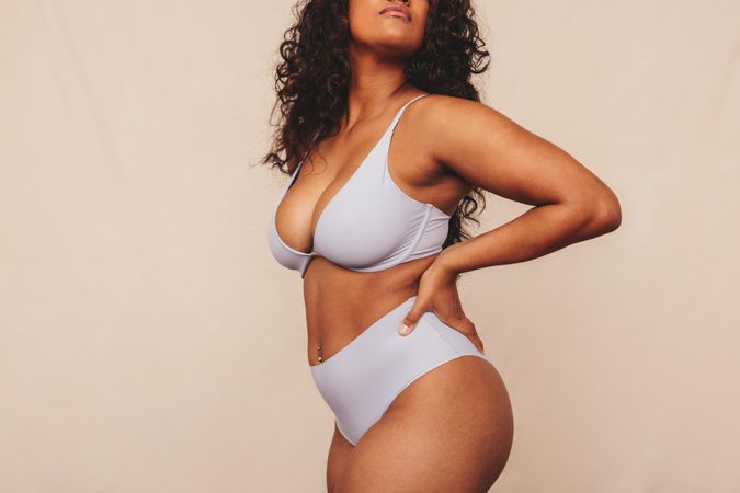 Anonymous young woman embracing her natural body and curves against a studio background