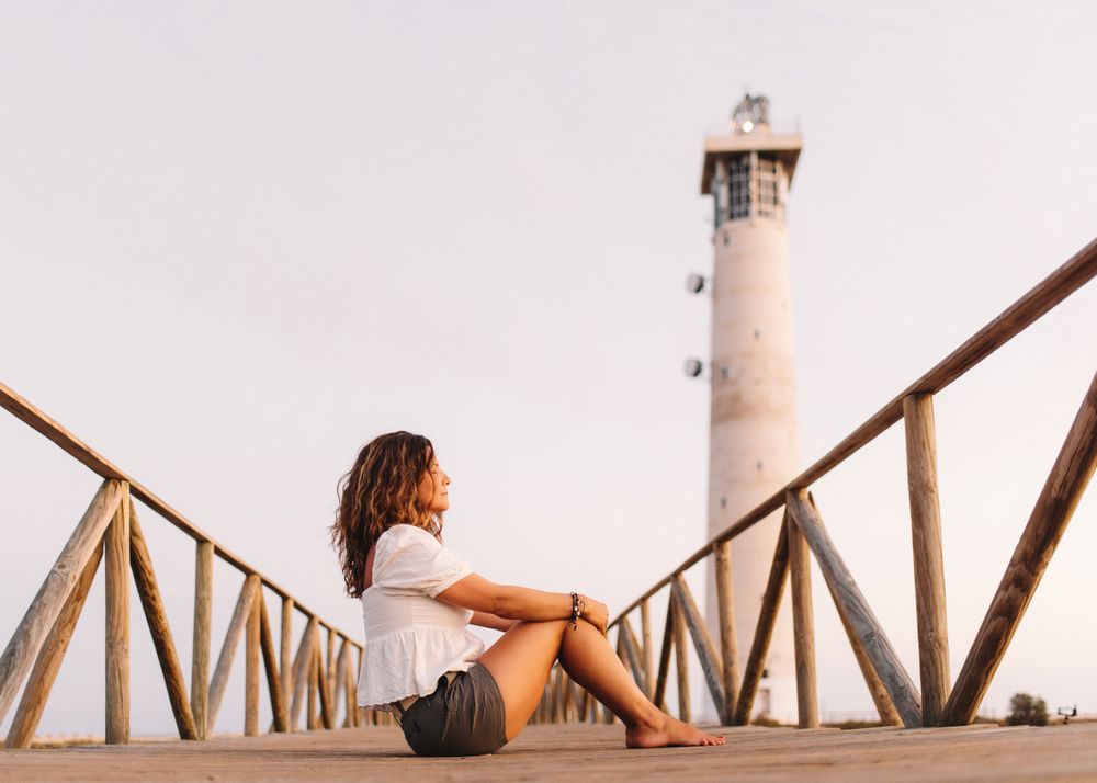 Woman sitting on bridge to lighthouse and looking away