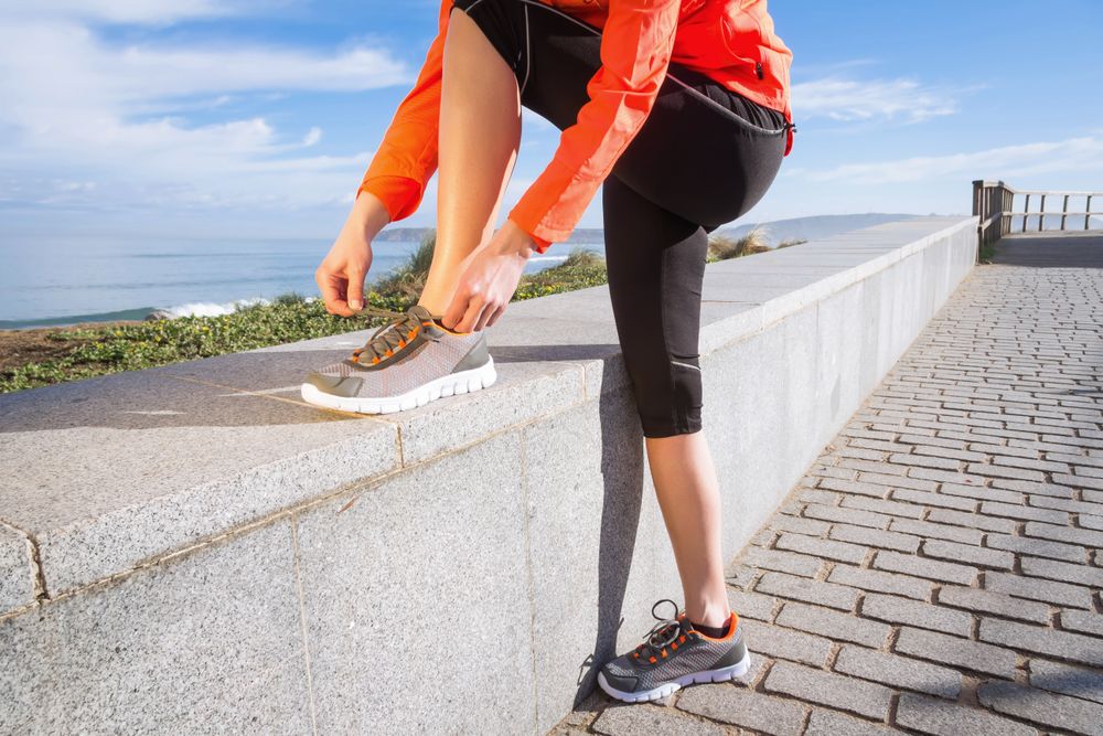 Fit woman tying shoes before work out on the beach