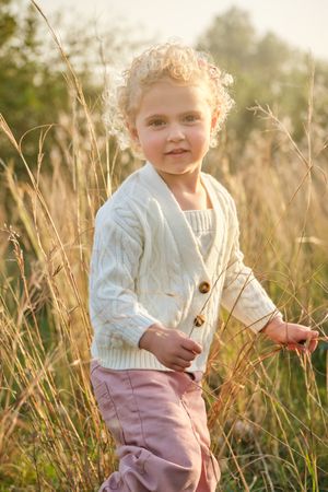 Cute little girl standing on lush meadow in nature