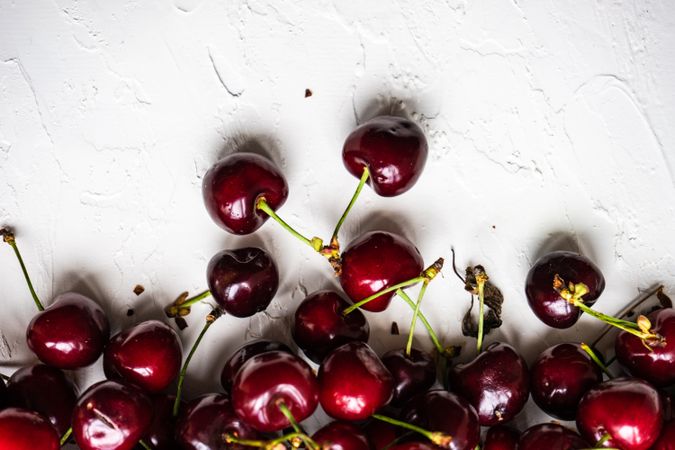 Top view of scattered sweet cherries on grey kitchen counter with copy space