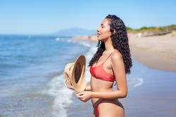A Woman is Relaxing and Enjoying a Joyful Day at the Beach while Wearing a Hat