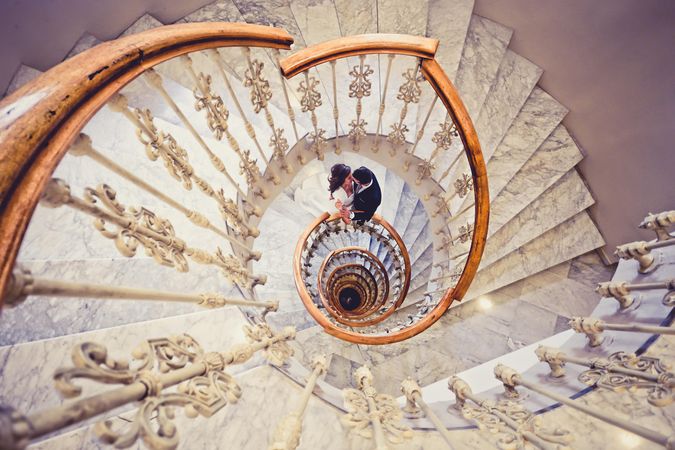 Looking down at spiral staircase with newly married couple kissing