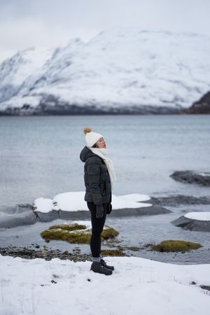 Young asian woman on pond shore against highland in winter