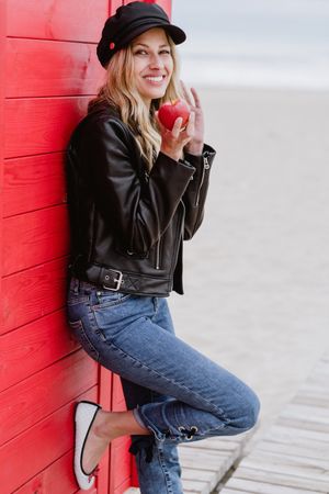Woman eating an apple near bright wooden cabins