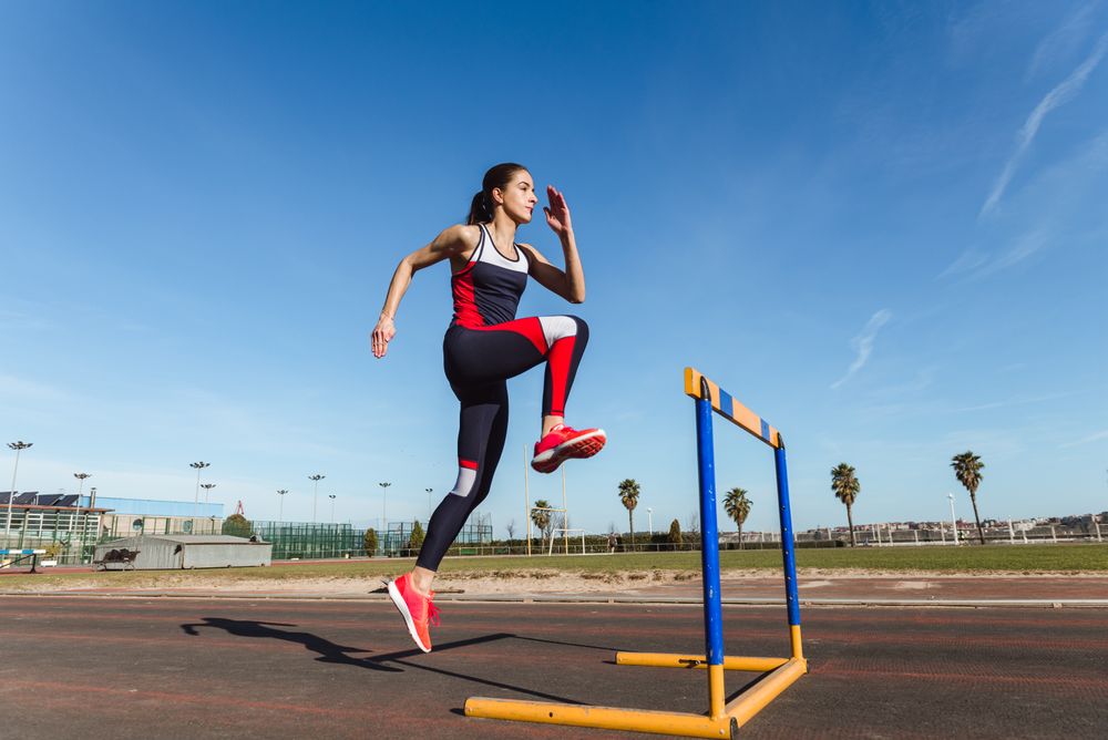 Female athlete hurdling on stadium